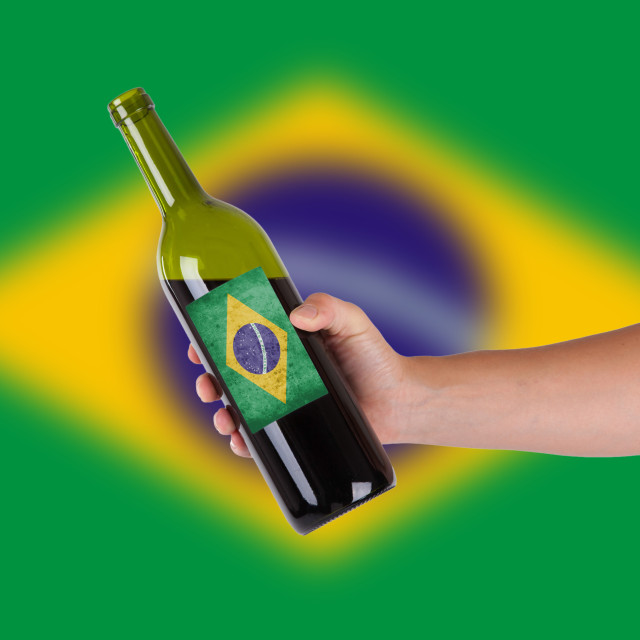 Hand holding a bottle of red wine, label of Brazil, isolated on white,