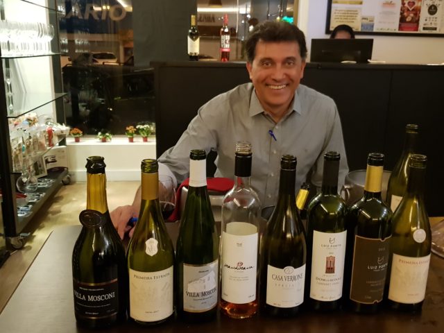 Antonio Coelho, editor do Decantando a Vida, posa ao lado dos vinhos mineiros de sua coleção